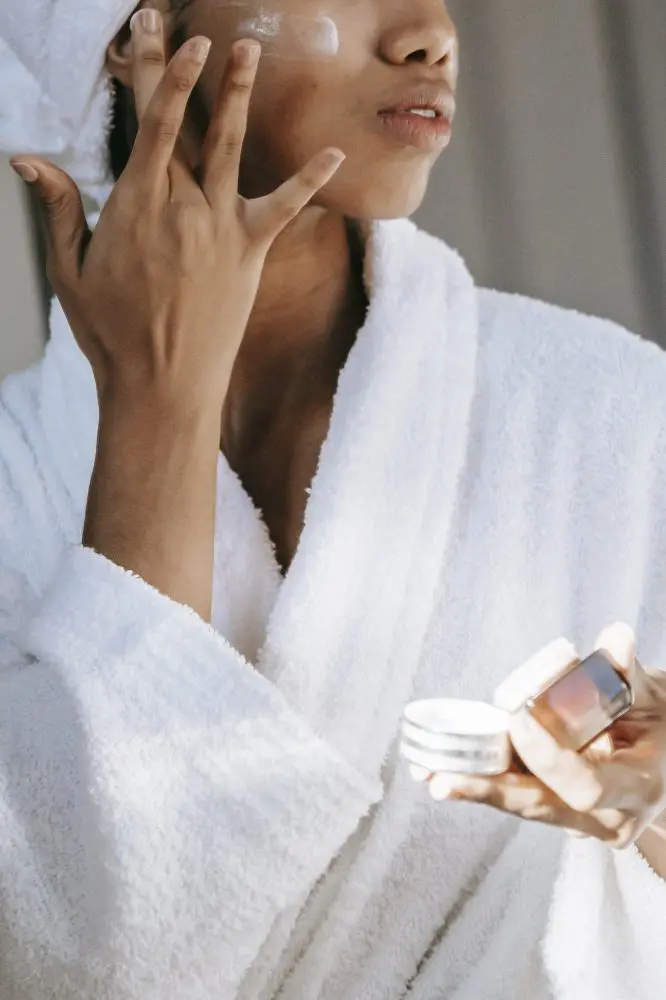 African american woman applying cream on face